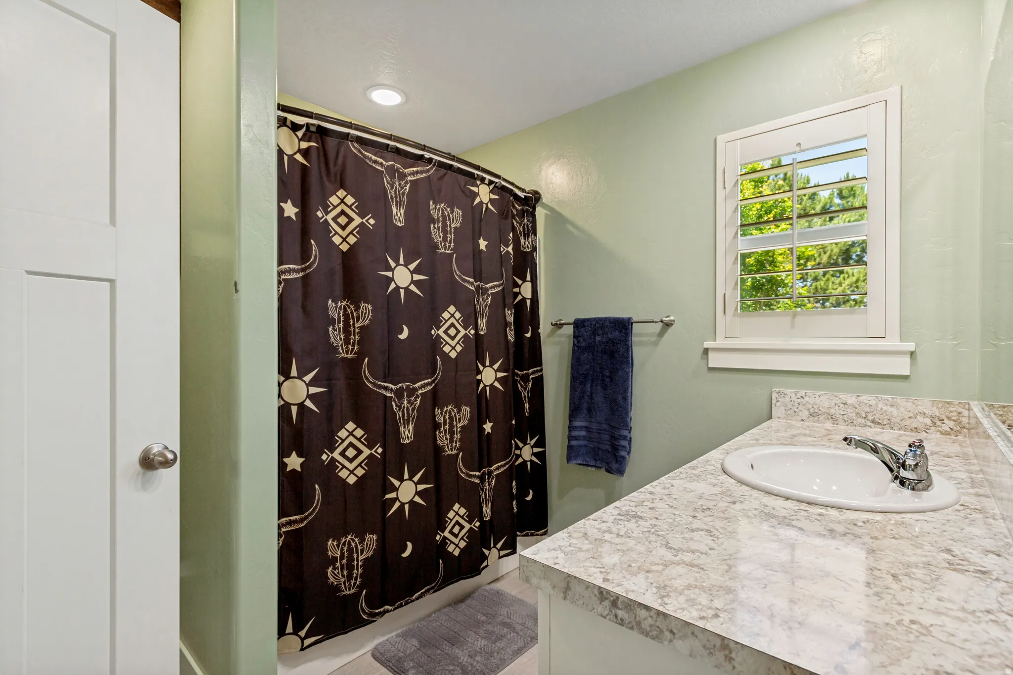 Bathroom vanity with a light-toned countertop, inset sink, and chrome faucet