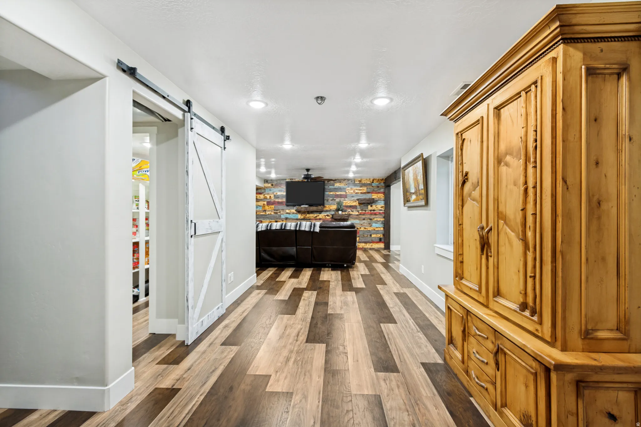 Spacious living area featuring wood-finish flooring, recessed lighting, and a decorative accent wall
