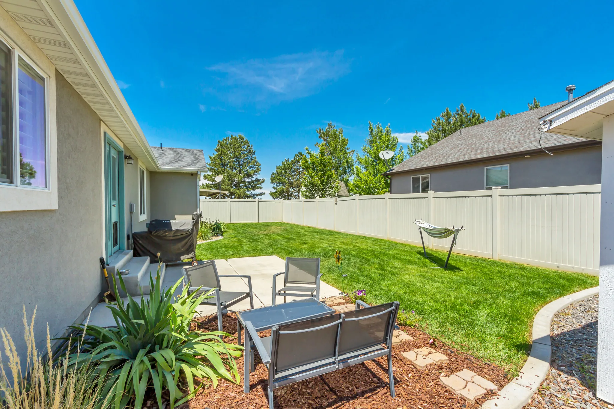 Expansive backyard featuring a manicured lawn, a concrete patio area, and a privacy fence