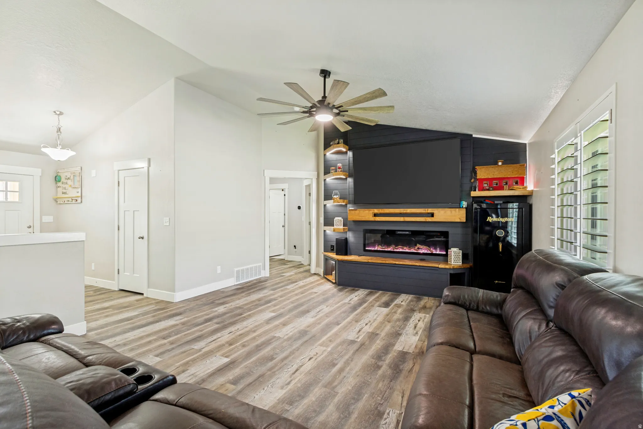 Spacious living area featuring wood-finish flooring, vaulted ceiling, and a custom entertainment wall
