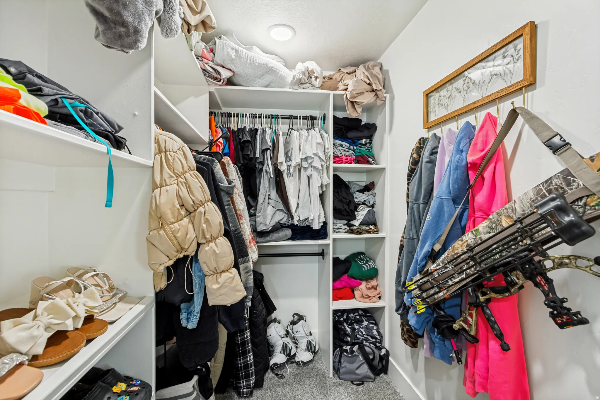 Walk-in closet featuring white built-in shelving, hanging rods, and a recessed ceiling light