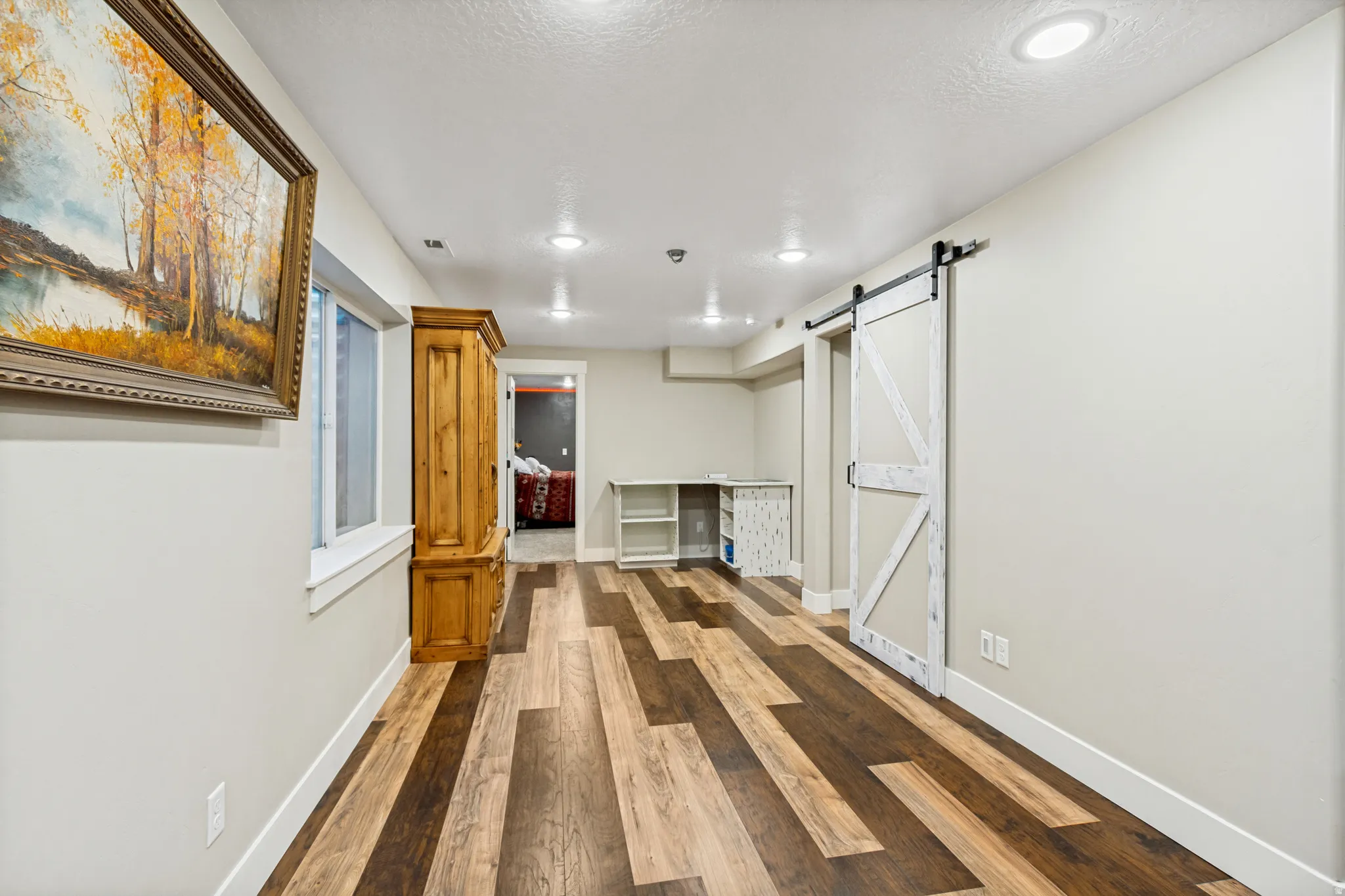 Spacious room featuring multi-toned wood-finish flooring and recessed lighting