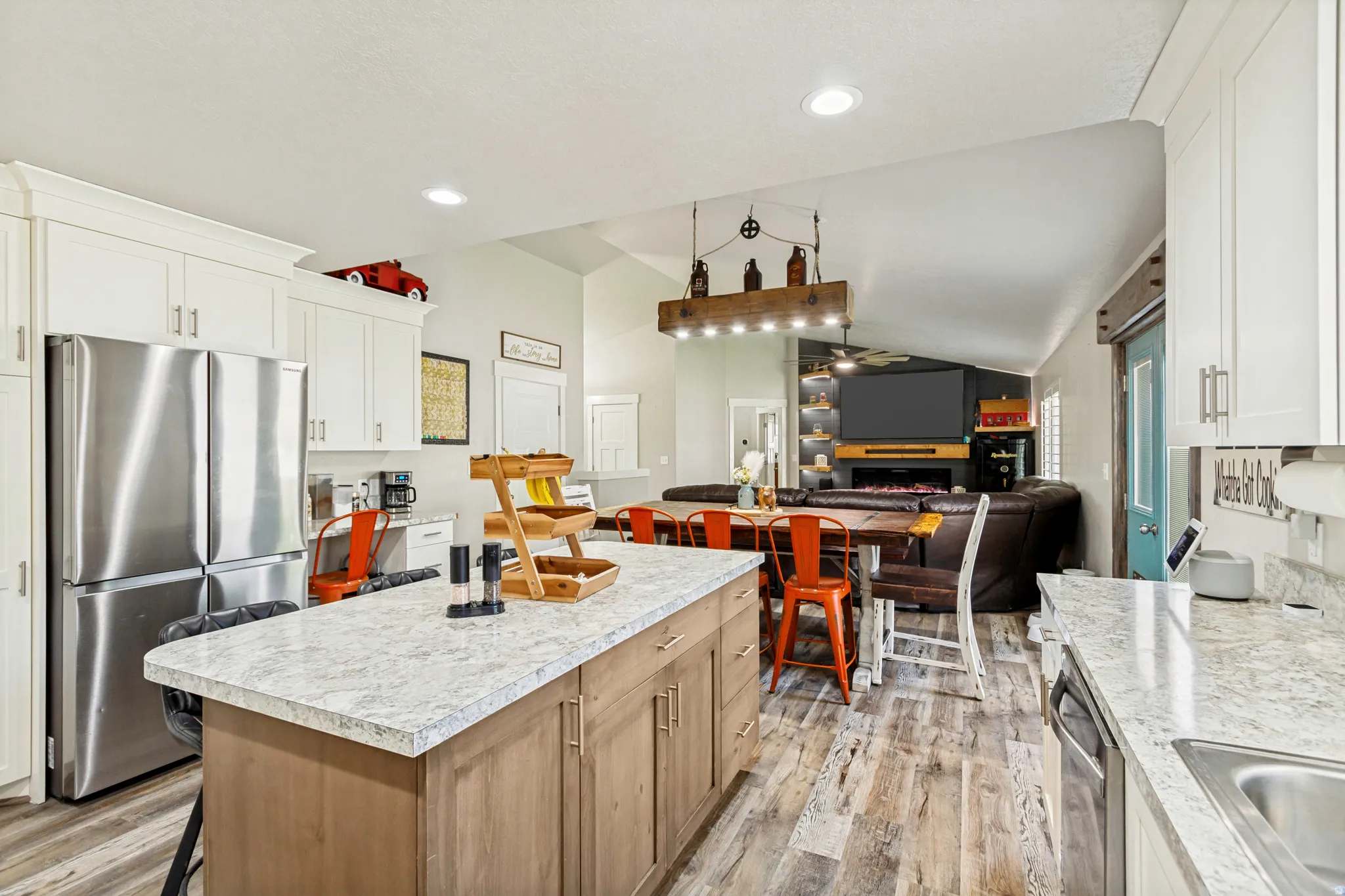 Open-concept kitchen featuring white shaker cabinetry, stainless steel appliances, and a central island with a light-toned countertop
