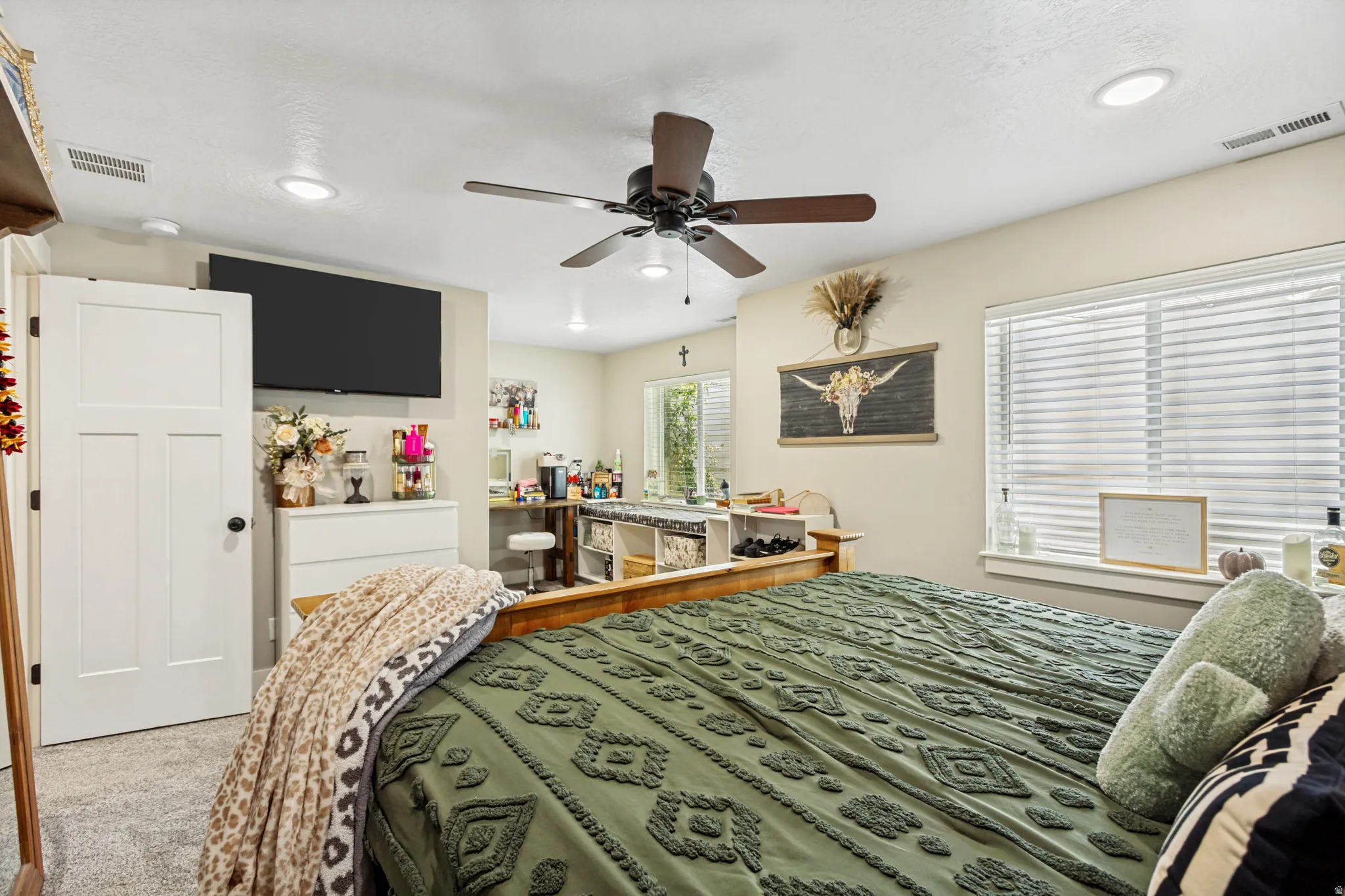 Carpeted interior space featuring a ceiling fan with integrated lighting, recessed lighting, and a white paneled door