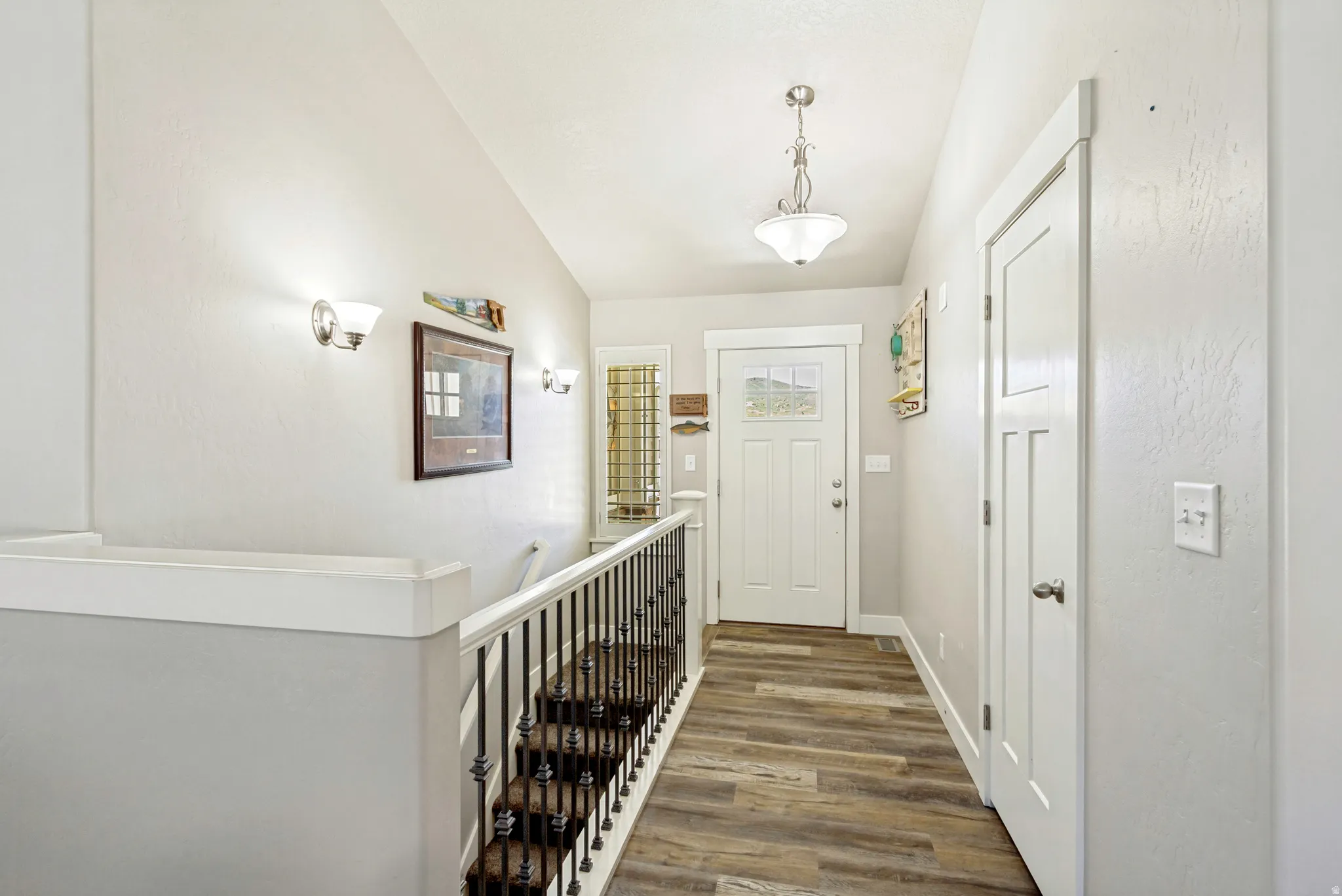 Inviting entryway featuring wood-finish flooring, a white paneled door with glass inserts, and a decorative overhead light fixture