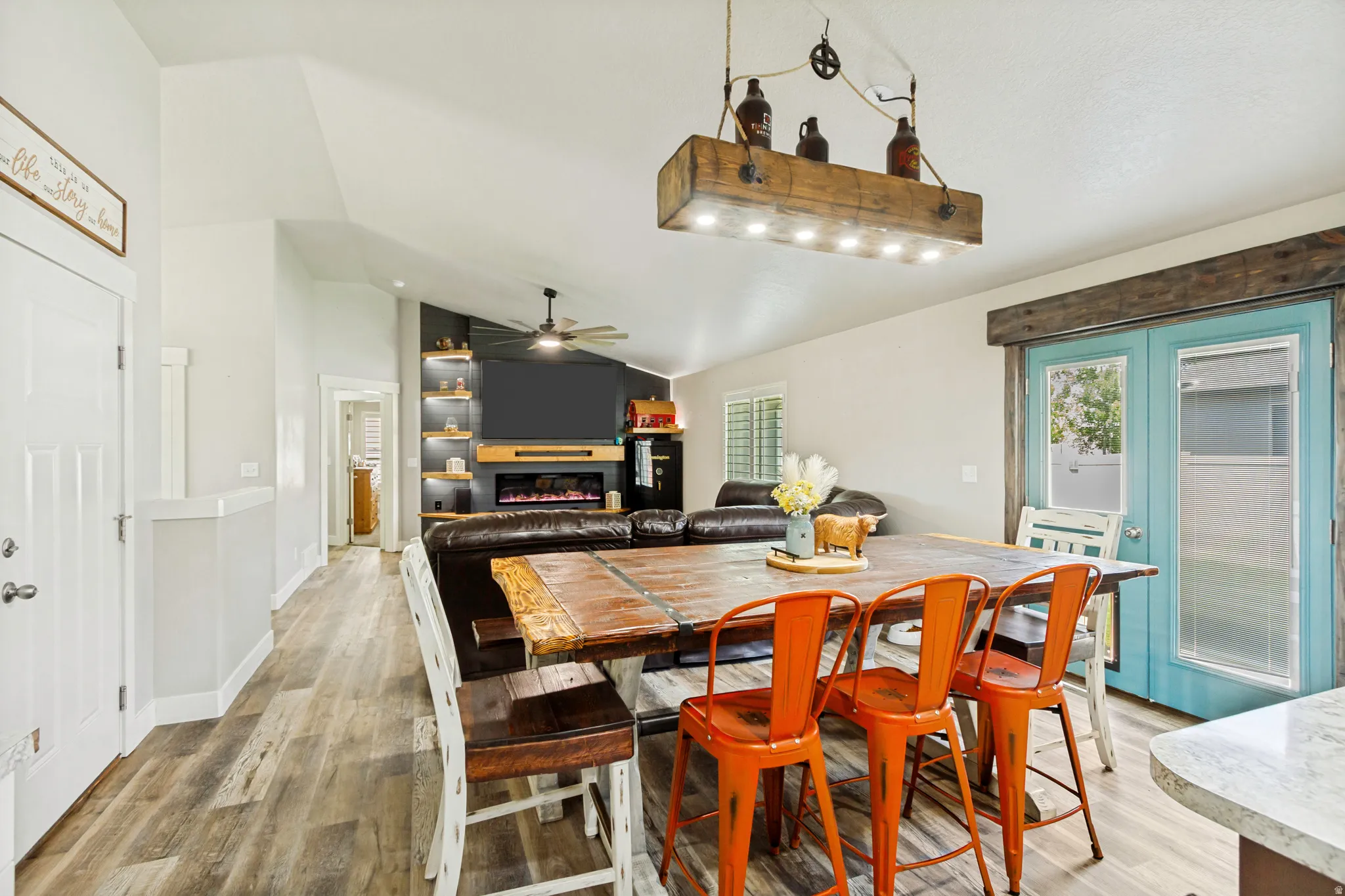 Open-concept living space featuring wood-finish flooring, a rustic-inspired dining table, and vaulted ceilings