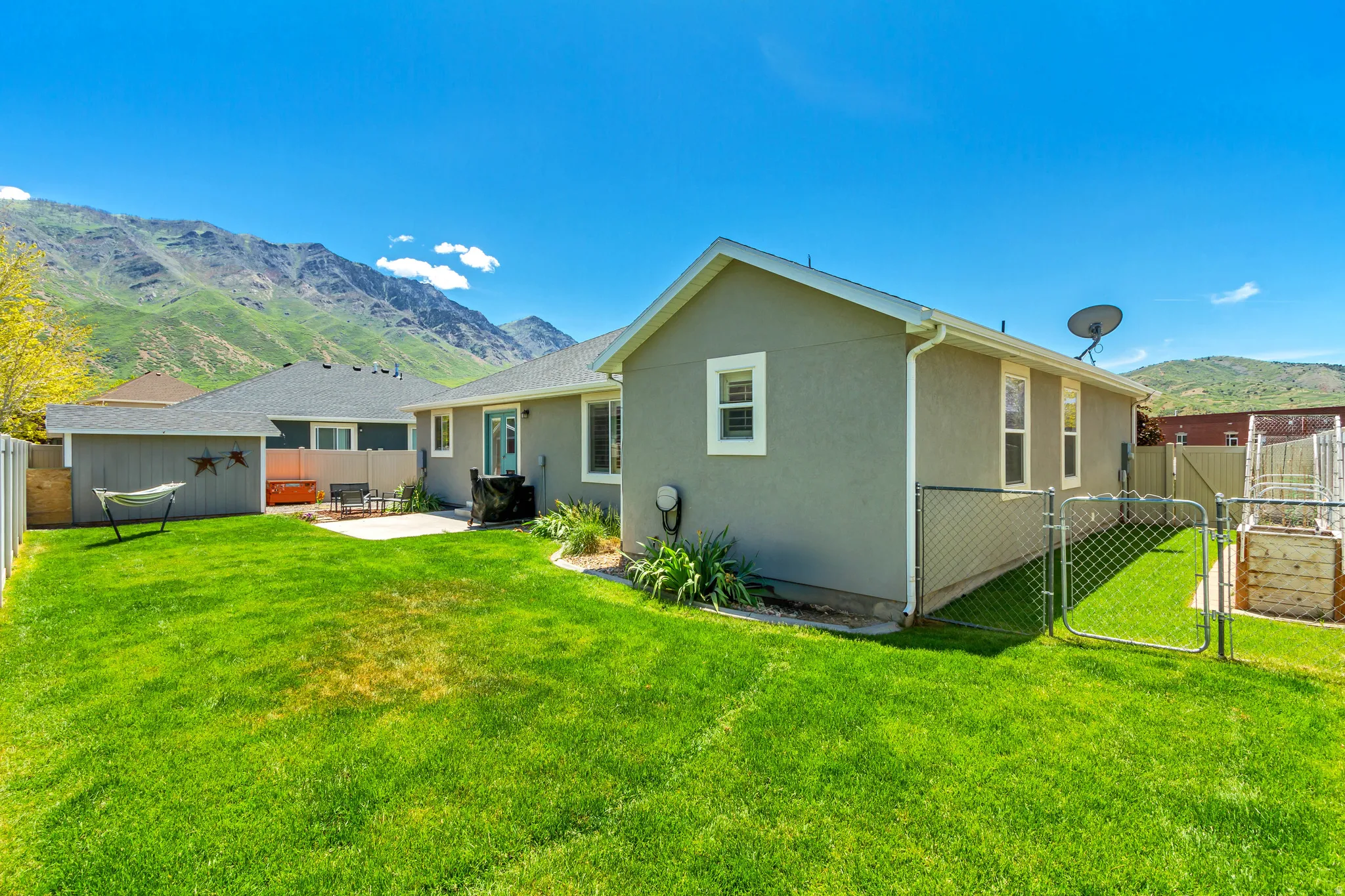 Expansive backyard featuring a lush lawn, concrete patio, and chain-link fencing