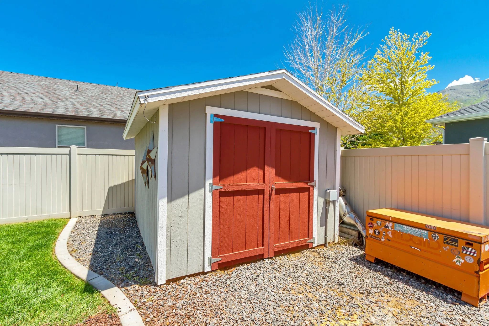Outdoor storage shed featuring a pitched roof, light gray siding, and red double doors