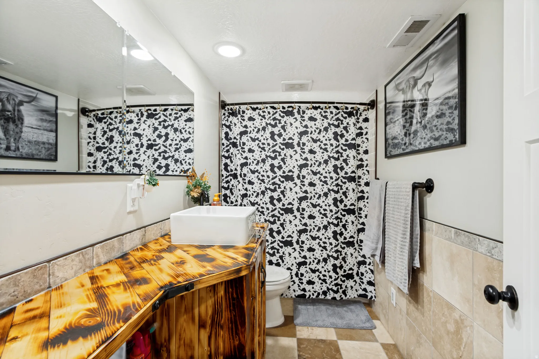 Bathroom featuring a vessel sink on a custom wood-finish vanity, a full-width mirror, and checkerboard floor tiling
