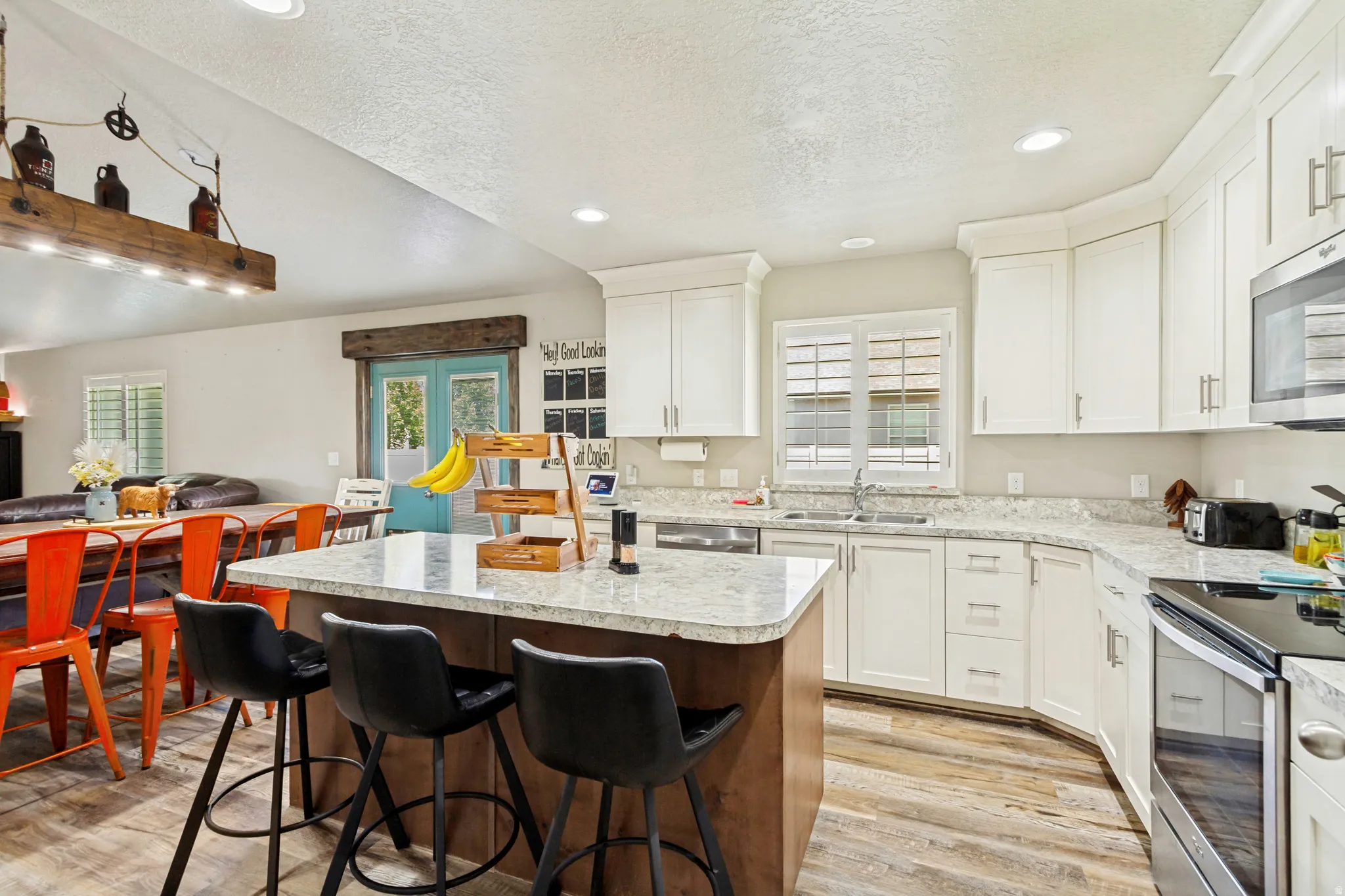 Kitchen featuring an island with seating, light countertops, white cabinetry, and stainless steel appliances