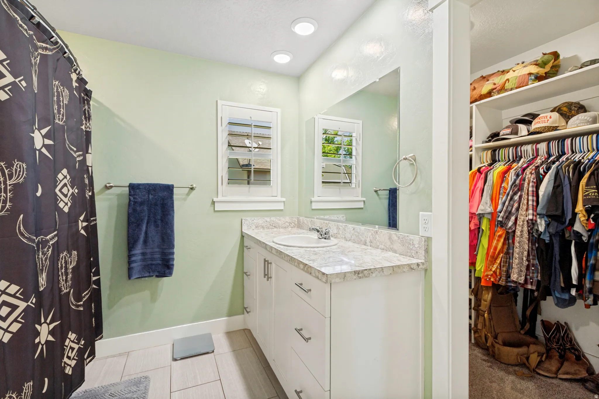 Bathroom featuring a single vanity with a light-colored countertop and integrated sink, under-cabinet storage, and an overhead mirror