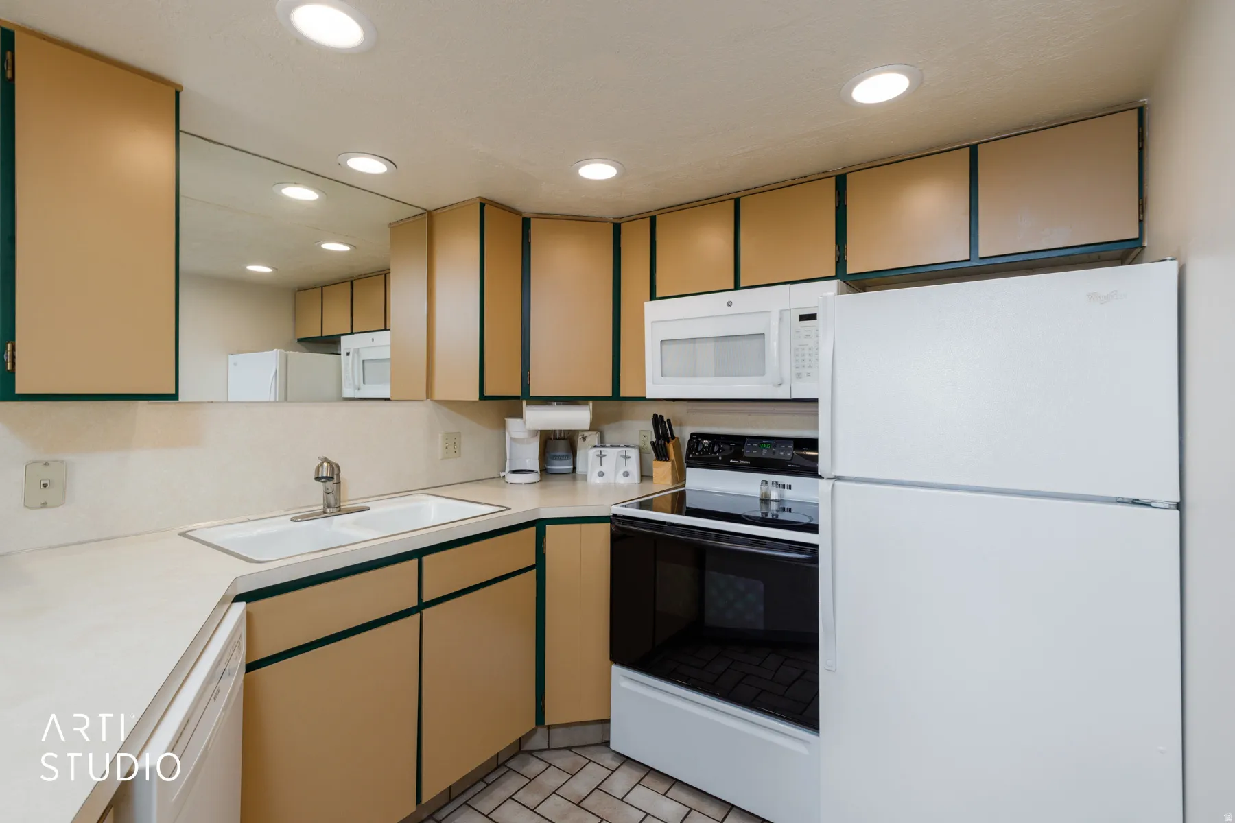 U-shaped kitchen featuring wood-finish cabinetry, white appliances, a white sink, and recessed lighting