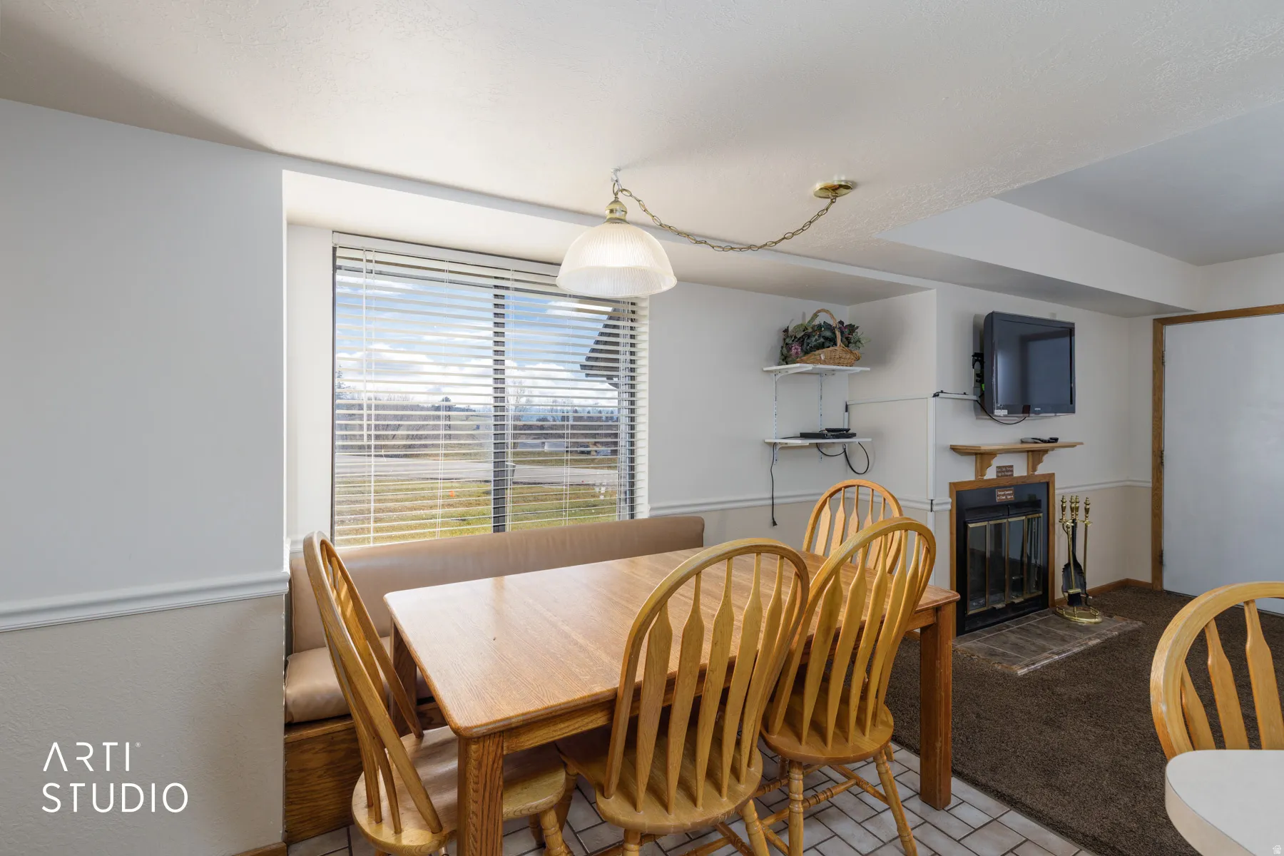 Dining area featuring a built-in banquette, a large window with blinds, a fireplace with a mantel, and mixed flooring of tile and carpet