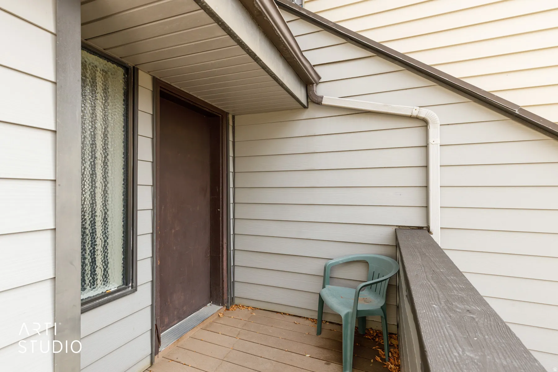 Covered outdoor balcony featuring horizontal siding and a dark paneled entry door