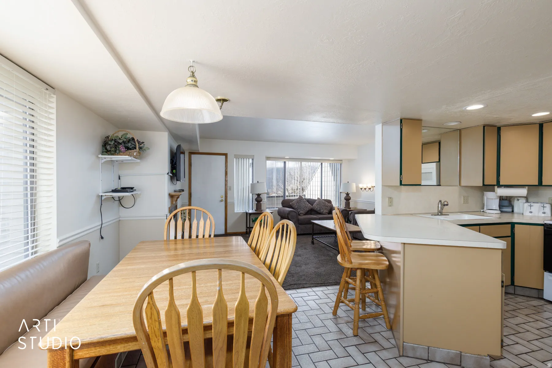 Open-concept living space featuring a kitchen with a peninsula and breakfast bar, white countertops, and a dining area with a built-in bench