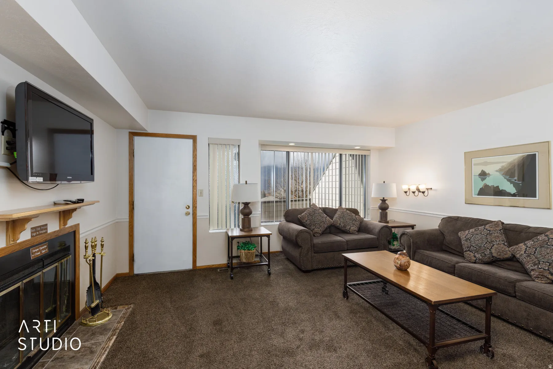 Living area featuring a fireplace with a wood mantle and dark-toned carpet flooring