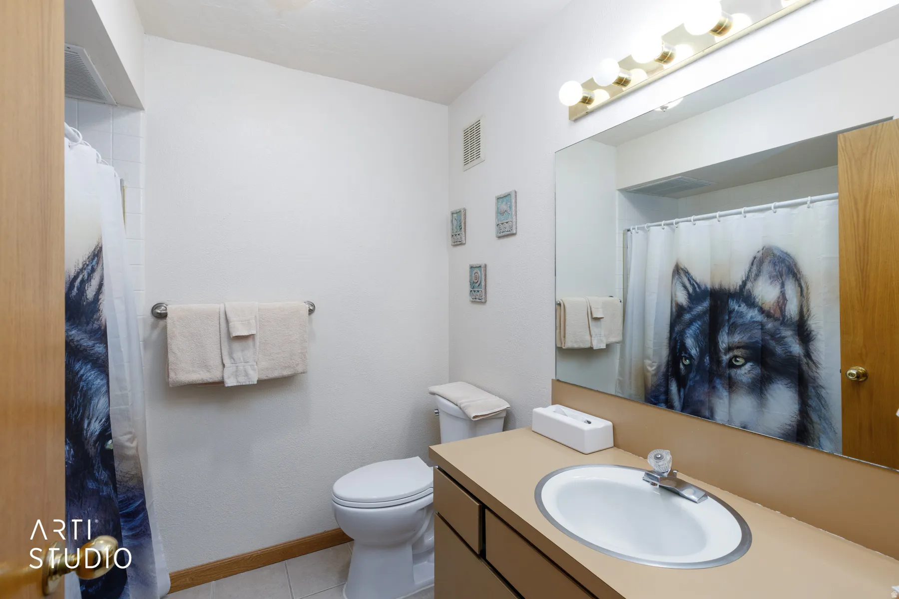 Bathroom featuring an integrated vanity sink with a laminate countertop, a large wall-mounted mirror, and a multi-bulb vanity light fixture