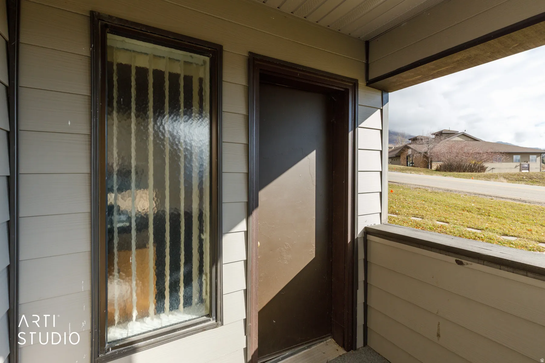 Exterior entry featuring horizontal siding, a solid brown door, and a textured glass sidelight with vertical mullions