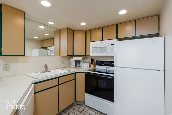 U-shaped kitchen featuring wood-finish cabinetry, white appliances, a white sink, and recessed lighting