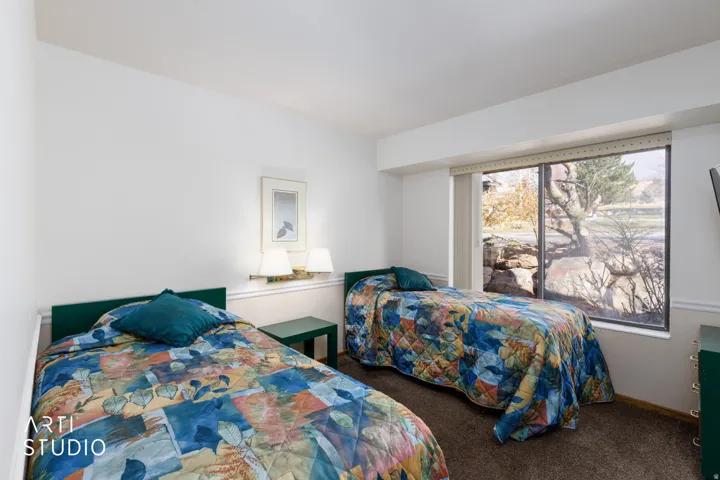 Bedroom featuring a large picture window, wall-mounted lighting, and neutral wall tones