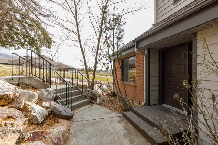 Concrete walkway leading to a multi-panel entry door with a covered porch