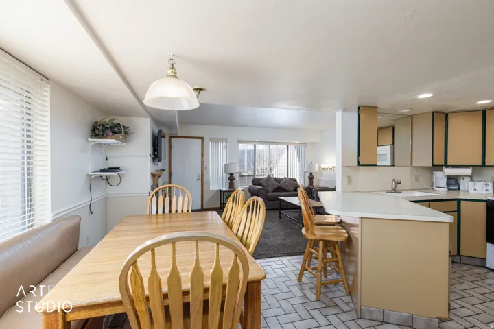 Open-concept living space featuring a kitchen with a peninsula and breakfast bar, white countertops, and a dining area with a built-in bench
