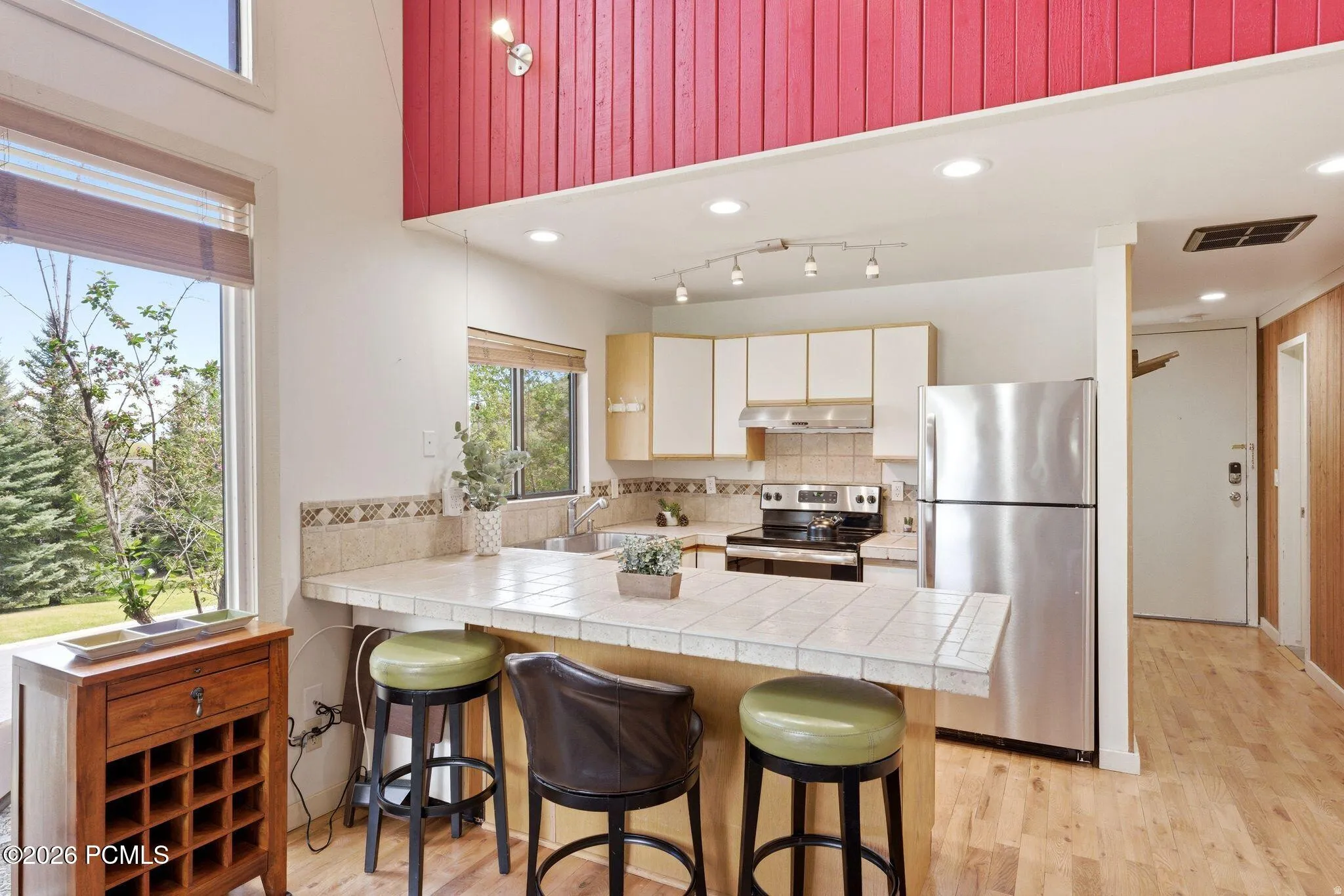 Kitchen area featuring a tile-top breakfast bar, white cabinetry, stainless steel appliances, and a wood-finish floor