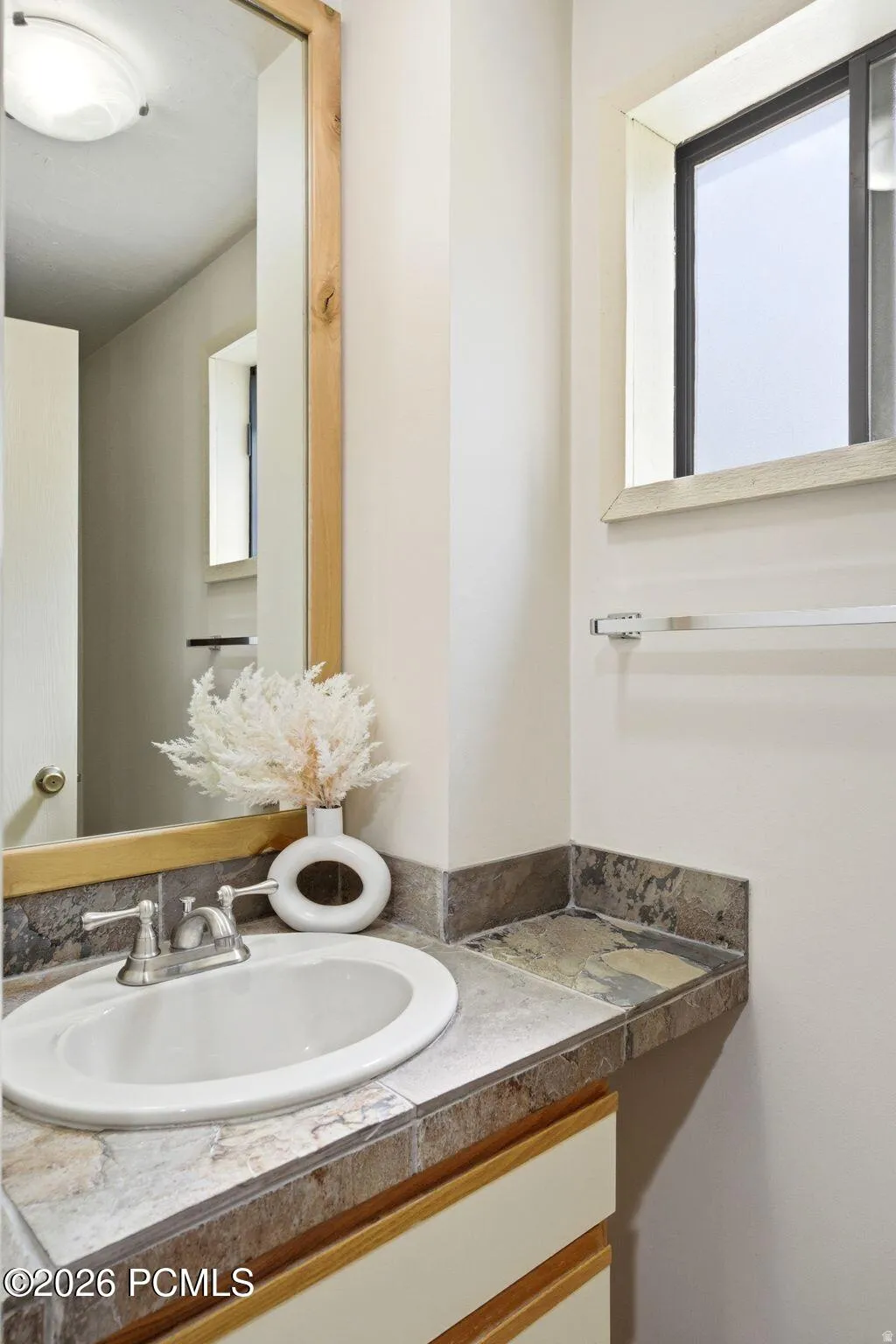 Vanity with an integrated sink and brushed nickel faucet, set within a natural stone tile countertop
