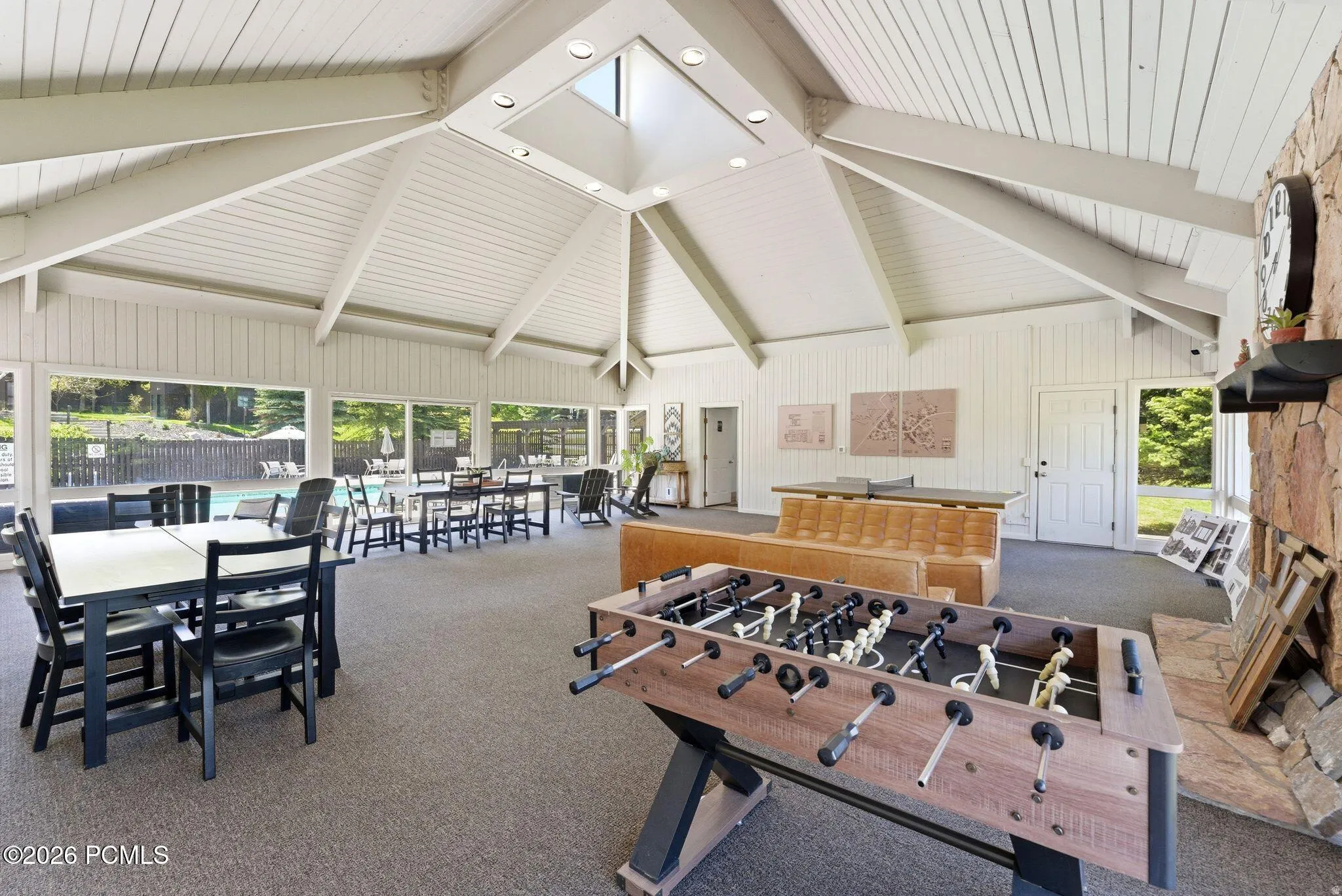Spacious recreation area featuring a vaulted ceiling with exposed beams, skylight, and recessed lighting