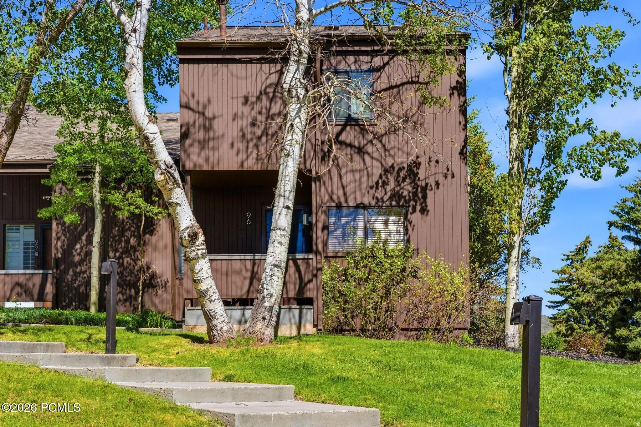 Multi-level brown vertical siding exterior with mature trees and landscaped grounds