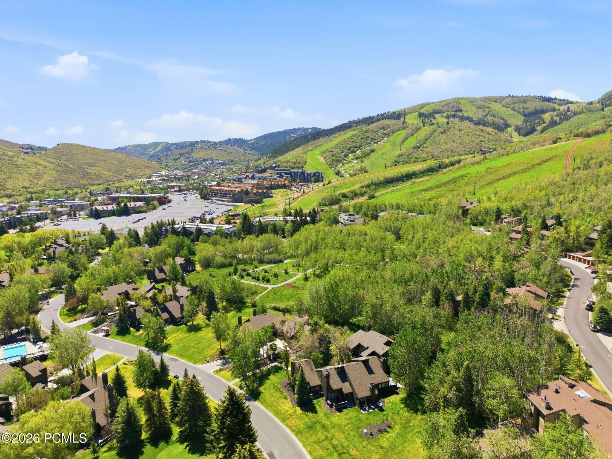 Aerial perspective showcasing a residential community nestled among lush green trees and rolling hills