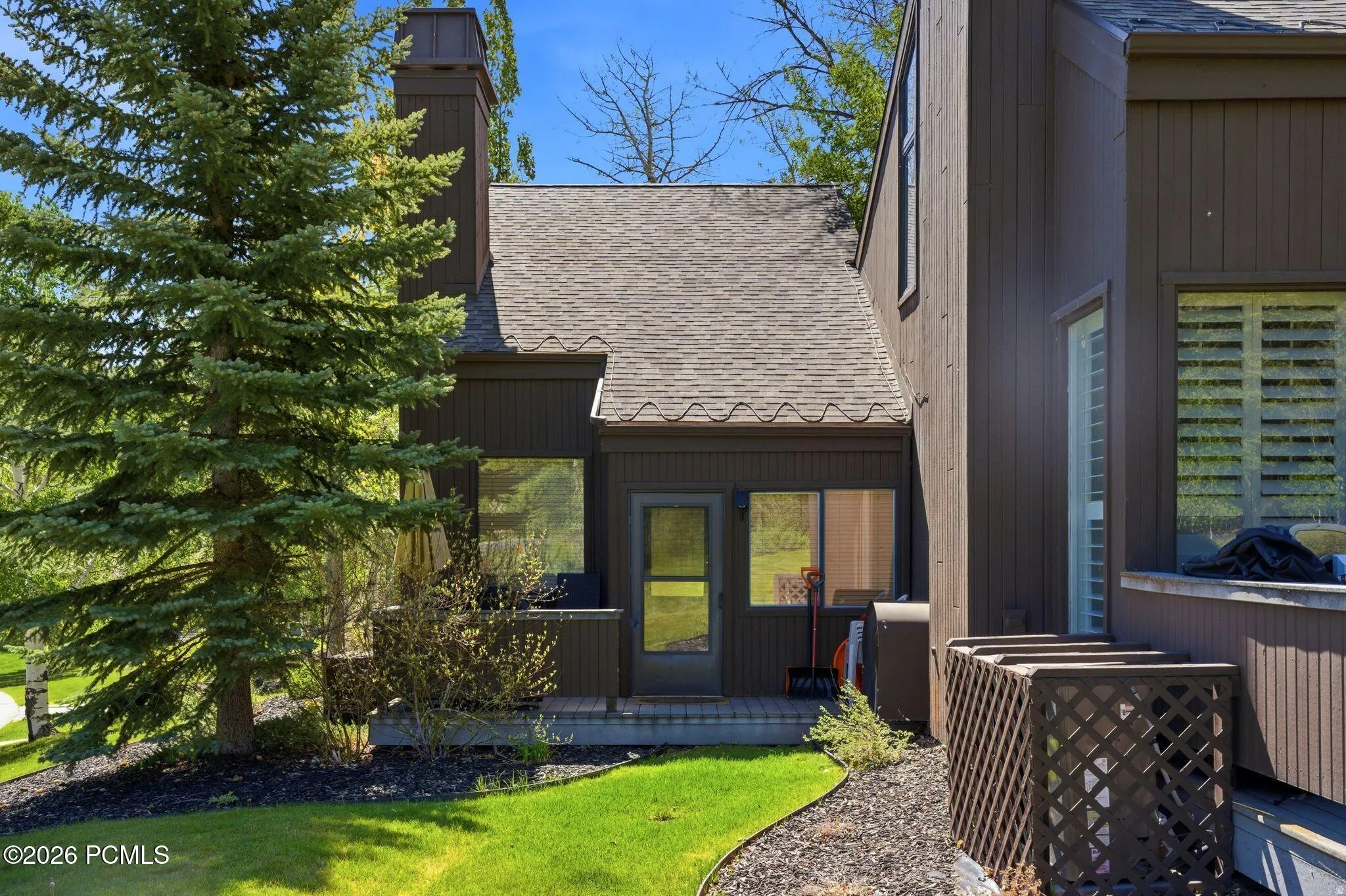 Brown exterior siding with a shingled roof and a prominent chimney