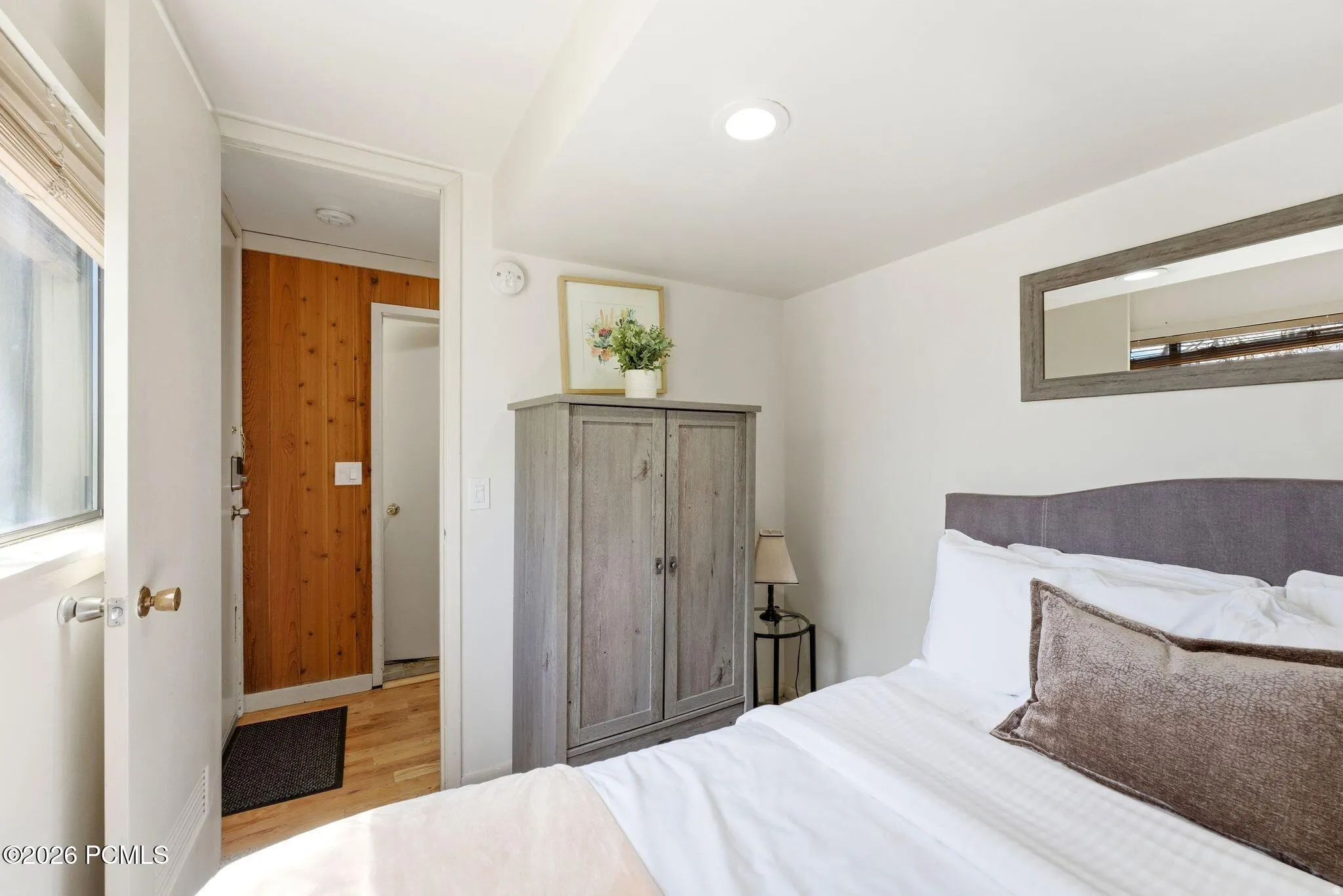 Recessed lighting illuminates this room featuring white walls and wood-finish flooring