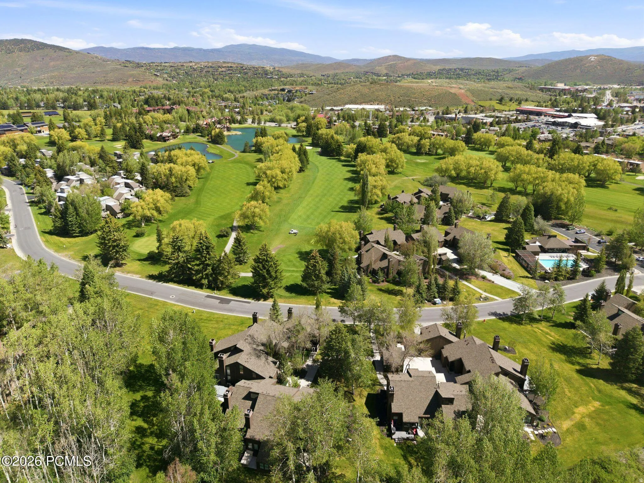 Aerial perspective showcasing a residential community with abundant mature trees and mountainous terrain