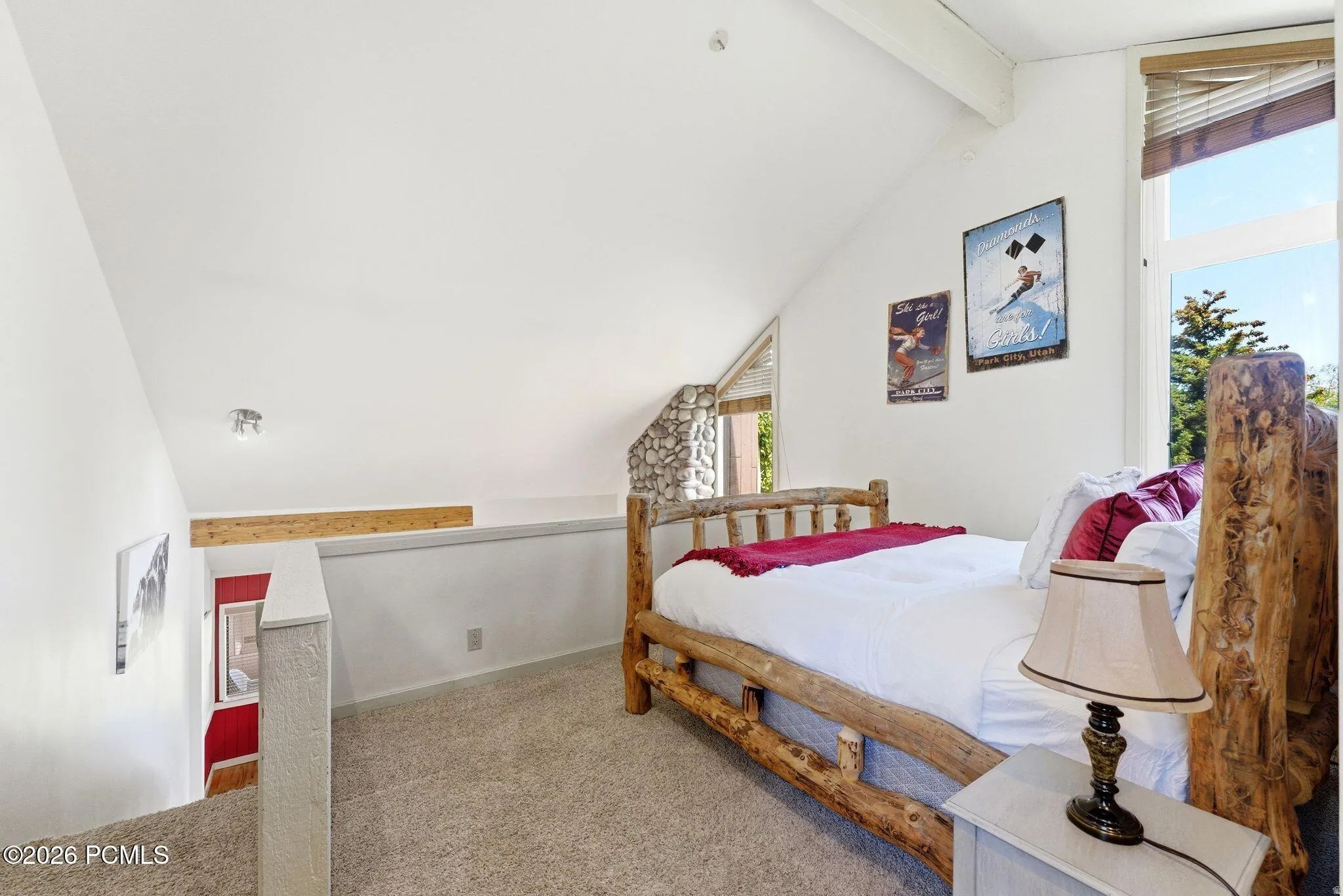 Loft bedroom with sloped ceilings, carpet flooring, and a large window with natural wood blinds