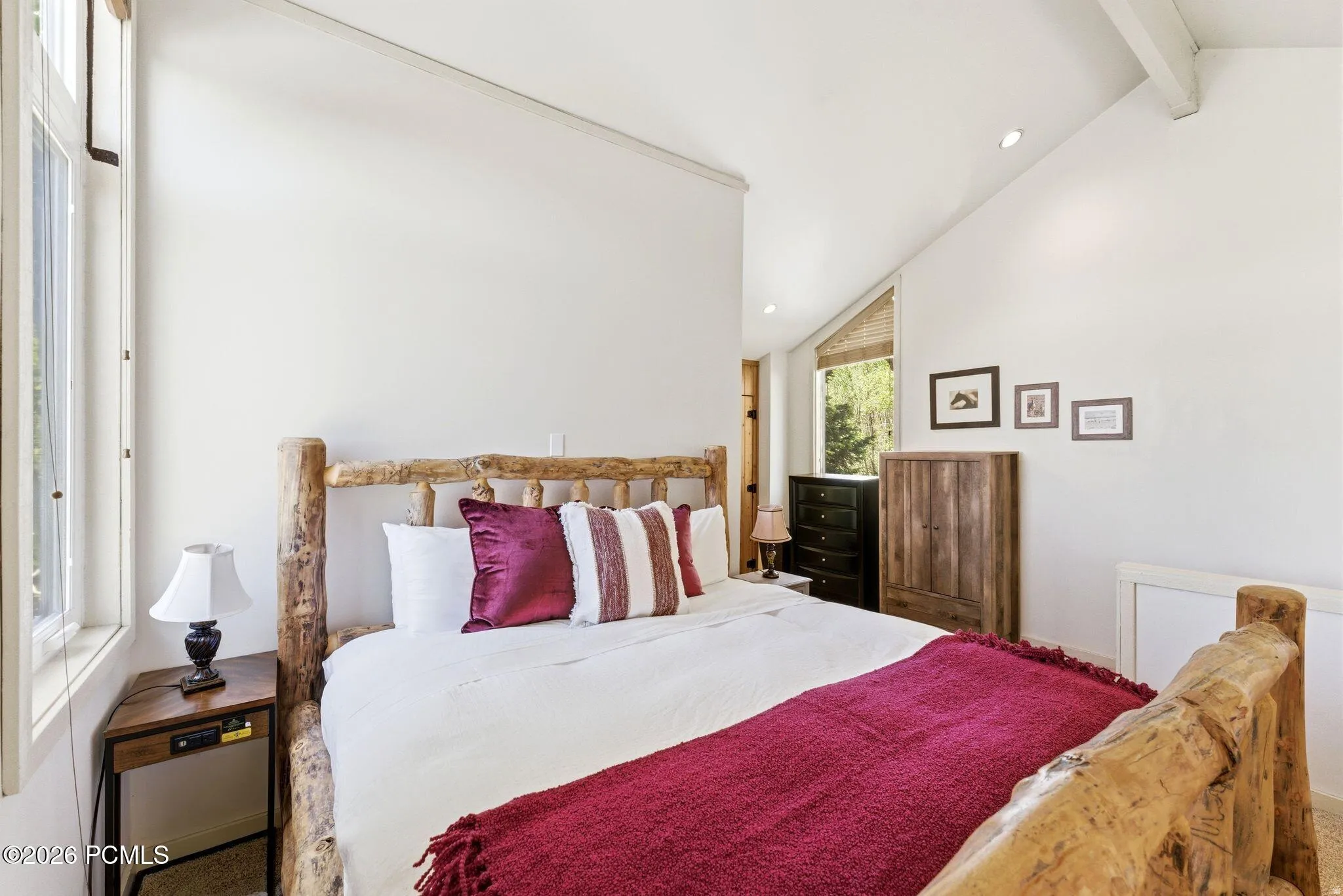 Vaulted ceiling with exposed beam, recessed lighting, and a large window providing natural light