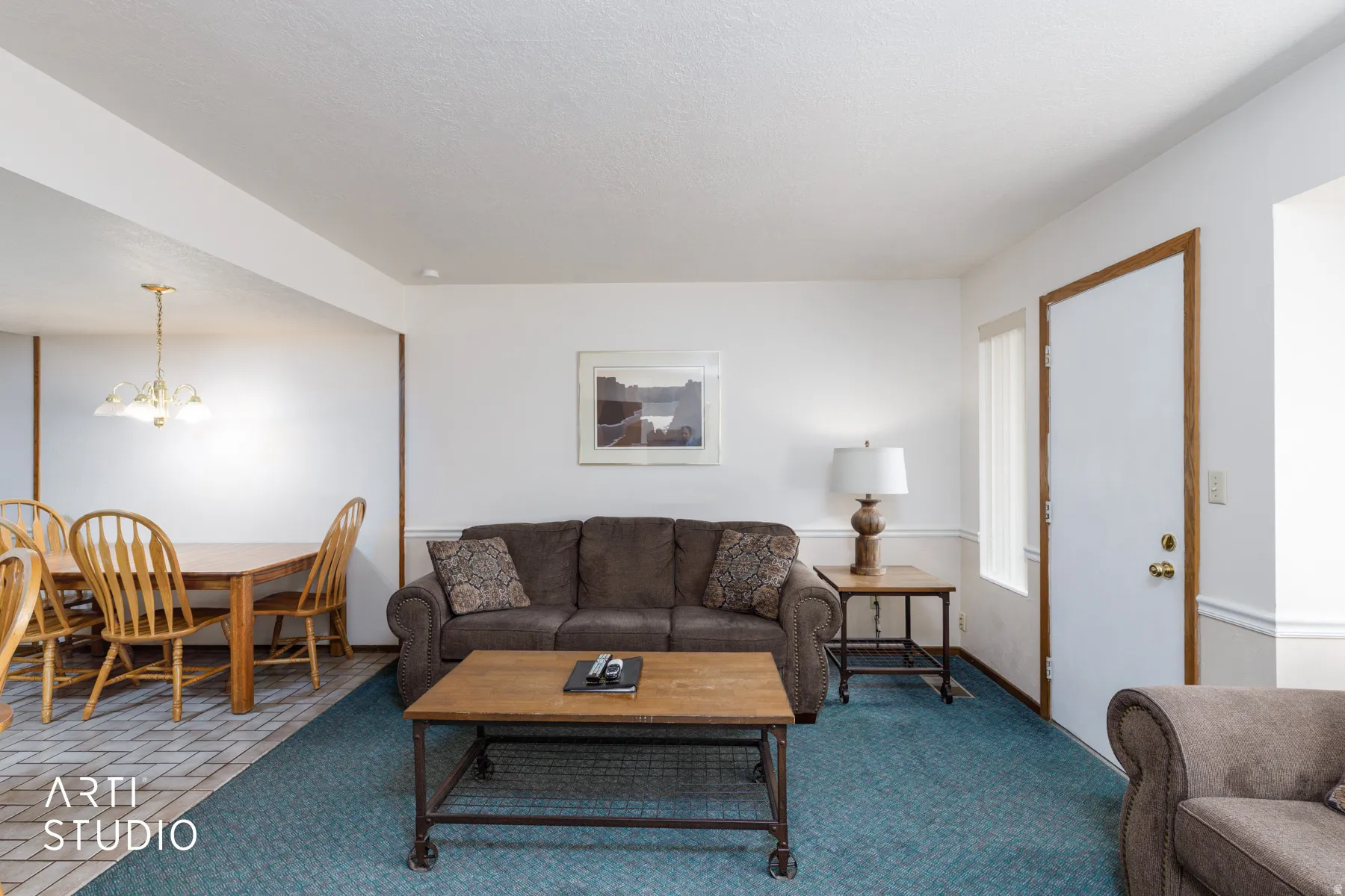 Bright living area featuring a neutral wall palette, wood-finish trim, and textured carpeting