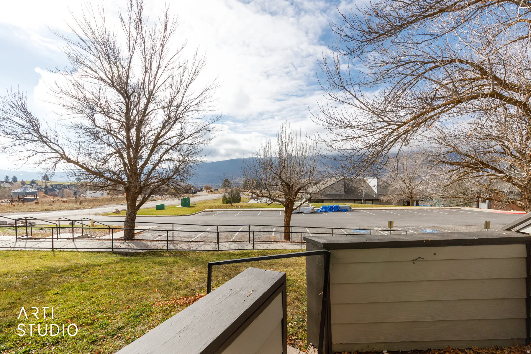 Expansive outdoor area featuring a manicured lawn, established trees, and surrounding mountain scenery