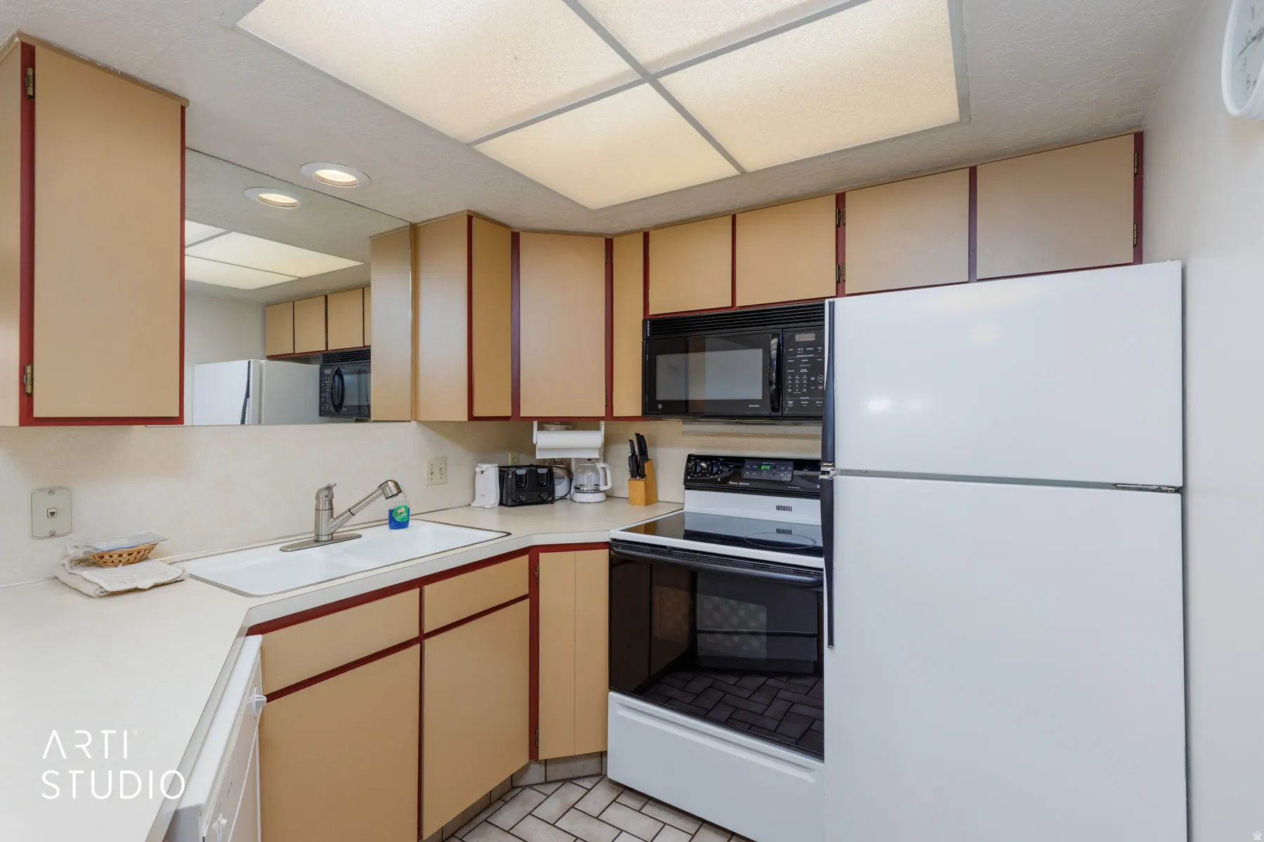 Kitchen featuring a white countertop with an undermount sink, beige cabinetry with red trim, and a white refrigerator