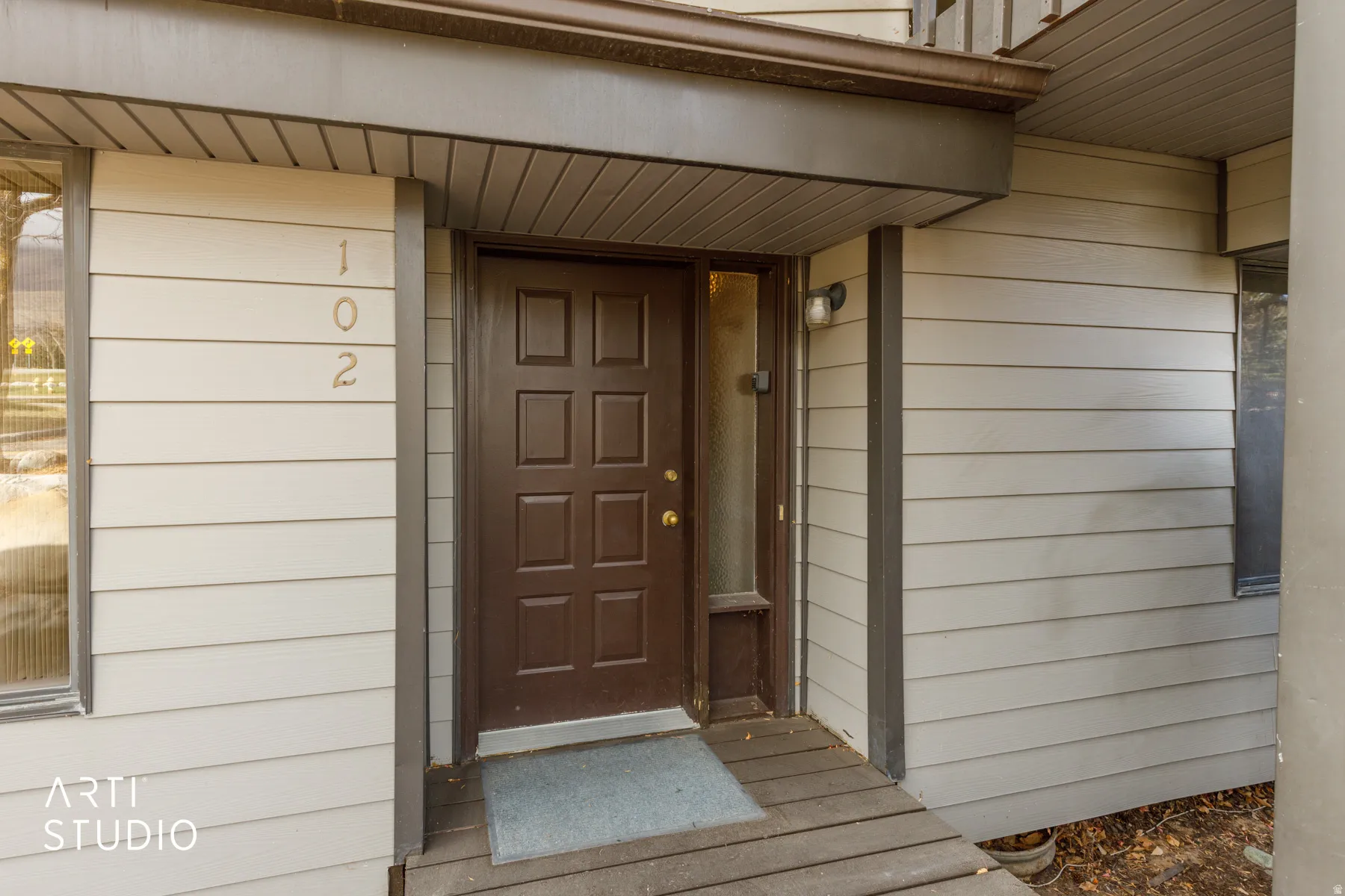 Entryway featuring a paneled door with sidelight, exterior wall sconce, and horizontal siding