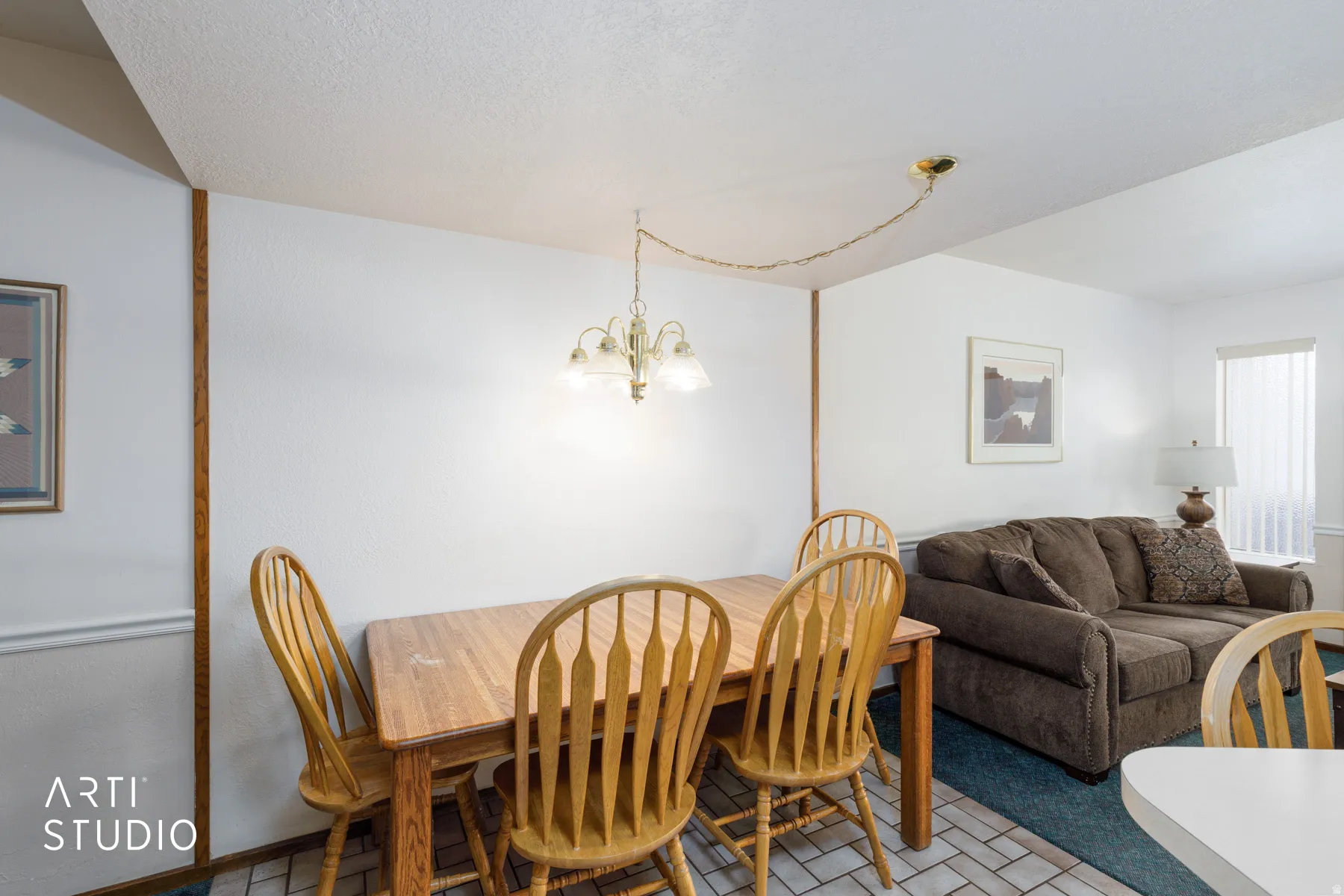 Open-concept living space featuring a dining area with a brass-finish chandelier and a patterned tile floor