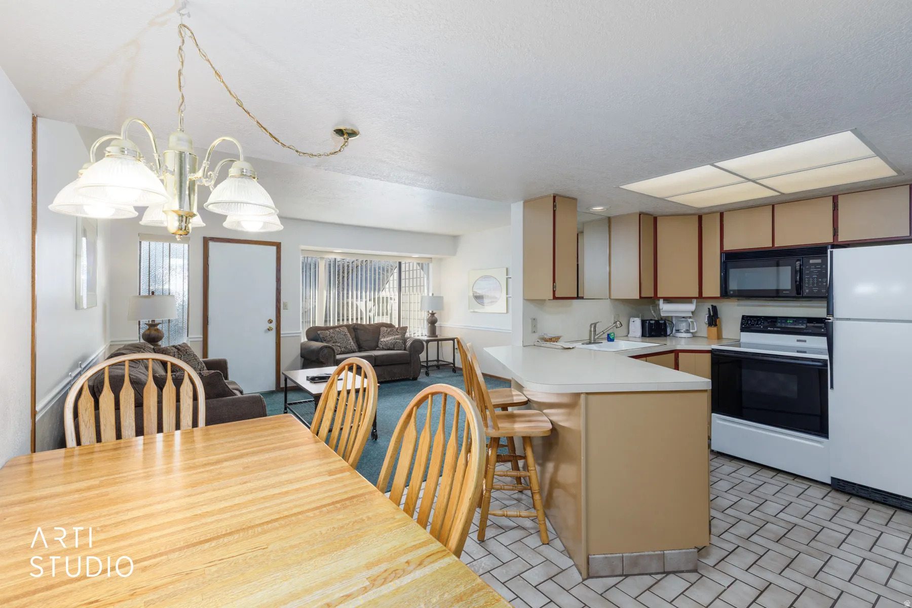 Open-concept kitchen and living area featuring a breakfast bar, white appliances, recessed ceiling lighting, and tile flooring