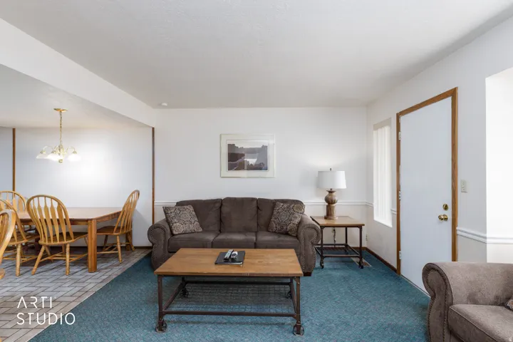 Bright living area featuring a neutral wall palette, wood-finish trim, and textured carpeting