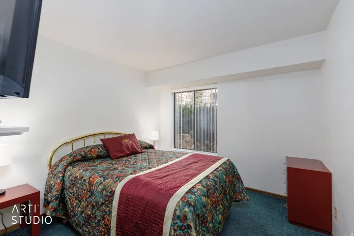 Bedroom featuring a window with vertical blinds, providing natural light