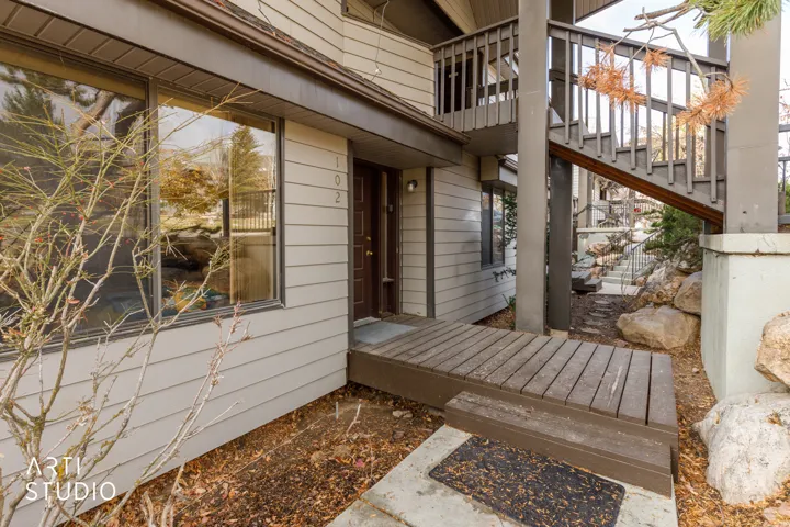 Exterior entrance featuring horizontal siding, a dark wood-finish entry door, and a wooden landing
