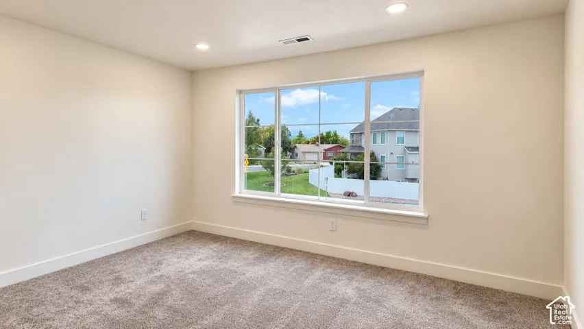 Neutral-toned room featuring wall-to-wall carpeting, recessed lighting, and a large multi-pane window