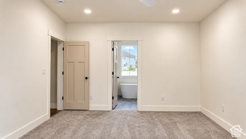 Neutral-toned interior space featuring recessed ceiling lighting, wall-to-wall carpeting, and solid-core interior doors with matte black hardware