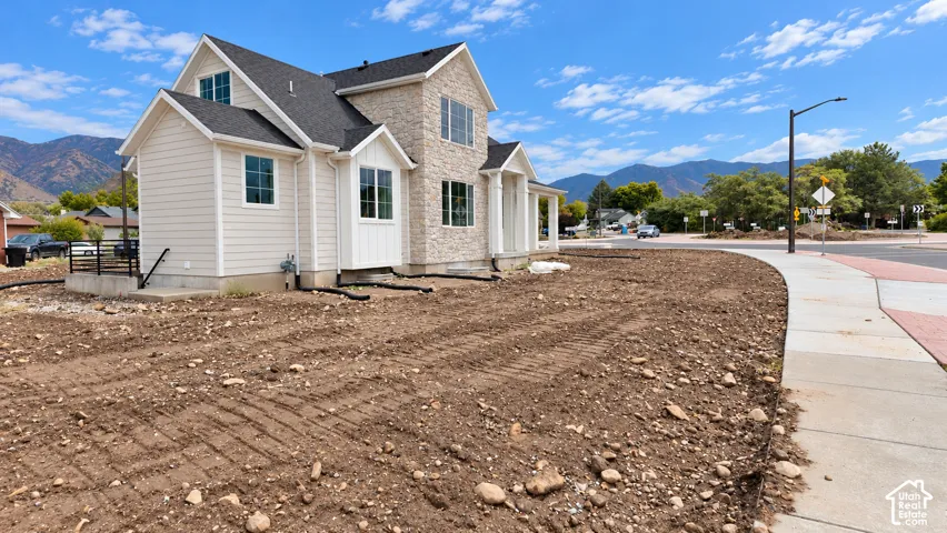 Exterior featuring horizontal siding, stone veneer masonry, multi-gabled rooflines, and mountain backdrop