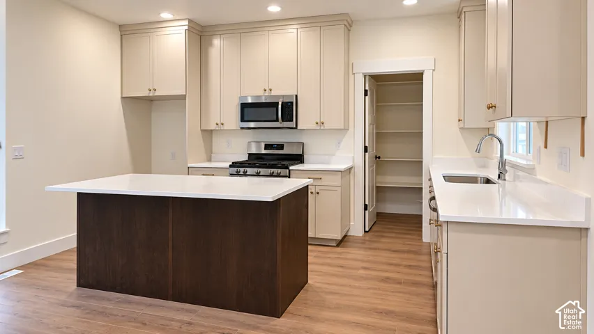 Kitchen featuring floor-to-ceiling cabinetry, a center island with a dark wood finish, light-toned stone countertops, recessed lighting, and a built-in walk-in pantry