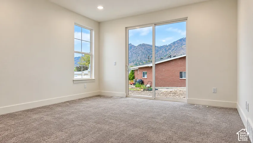 Room featuring wall-to-wall carpeting, recessed lighting, a single-hung window, and a sliding glass door with mountain scenery